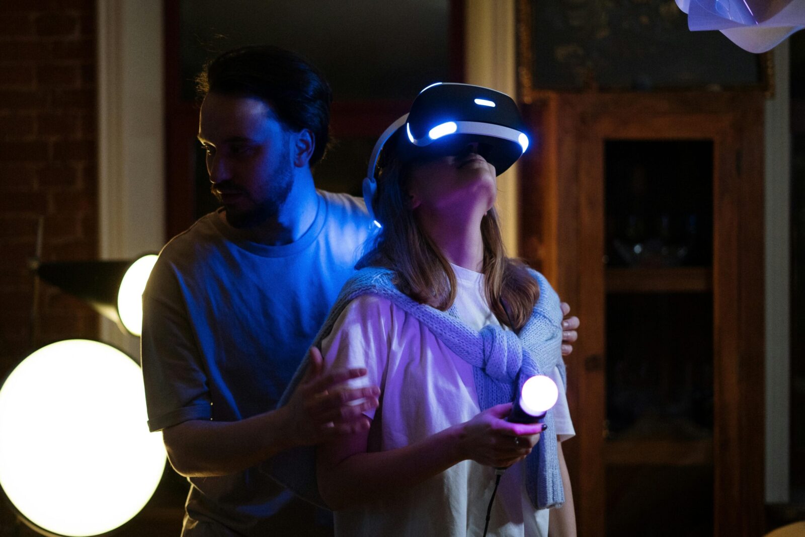A couple experiences virtual reality gaming with headsets and controllers in a cozy home setting.