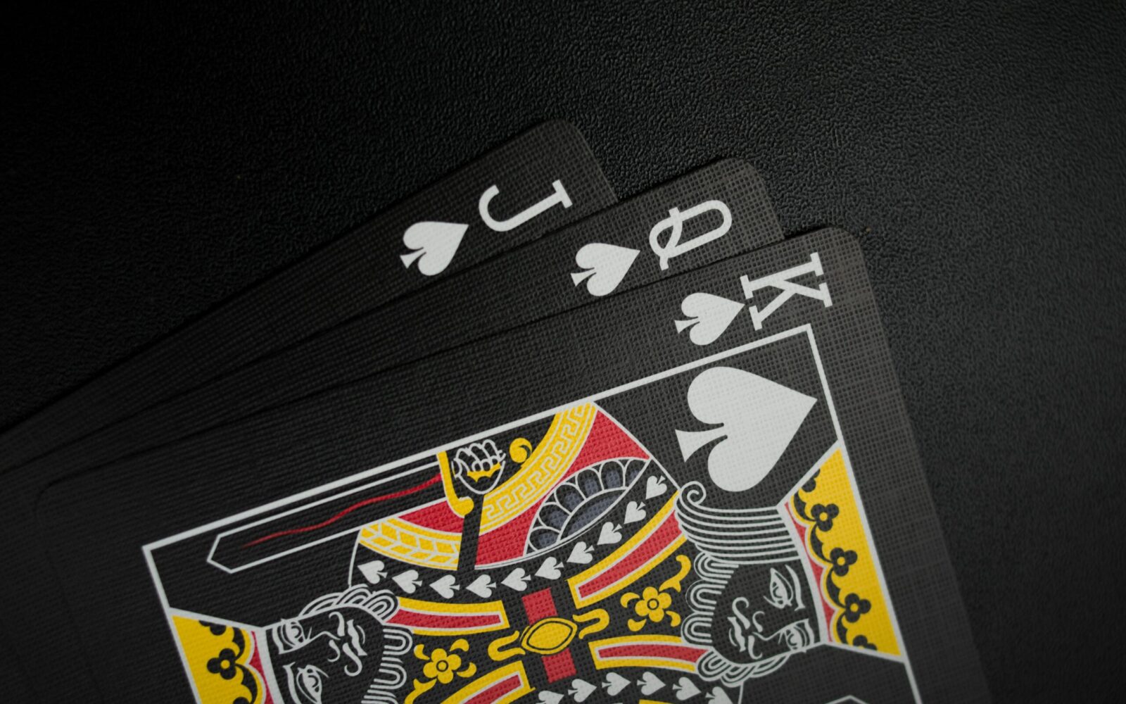 Close-up of black playing cards with focus on the King of Spades in a spade hand.