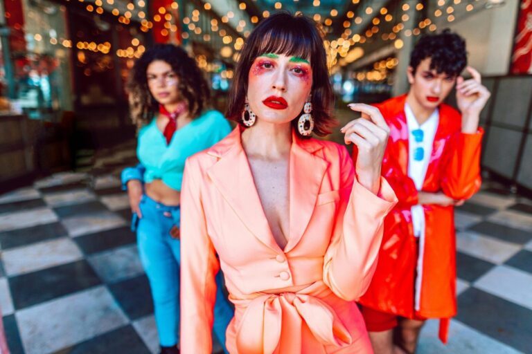 Stylish individuals in brightly colored outfits posing fashionably indoors with bokeh lights.